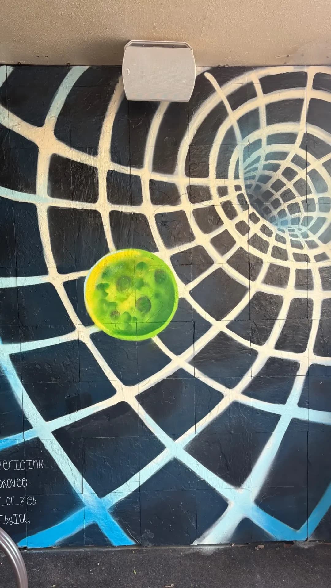 A mural inside the venue: a spiderweb in blue and white spray paint with a bright green moon.